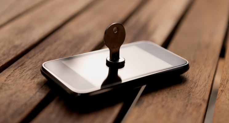 A smartphone placed on a wooden table, with a key inserted into the screen, symbolizing security, access, and digital protection.