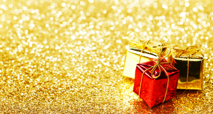 Two golden mini presents positioned next to a red mini present on a glitter background, representing a festive and celebratory atmosphere.